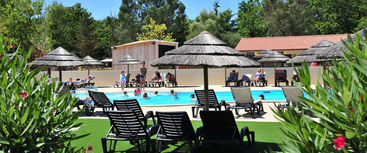 Vue de la piscine avec transats et paillottes au camping Tastesoule dans le Médoc