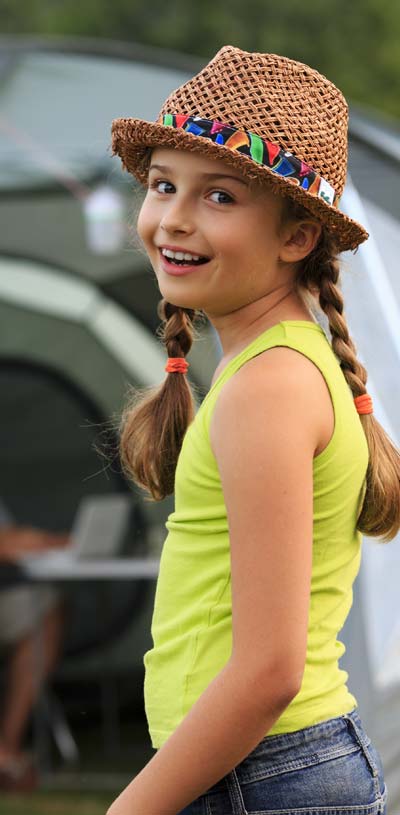 Fillette avec chapeau et nattes devant une tente au camping Tastesoule