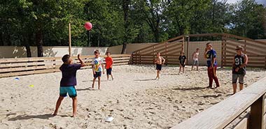 Enfants jouant au volley-ball sur le terrain multisports du camping Tastesoule