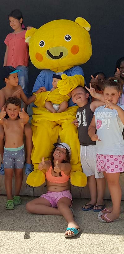 Mizzy la mascotte du camping Tastesoule entourée d'enfants dans le Médoc
